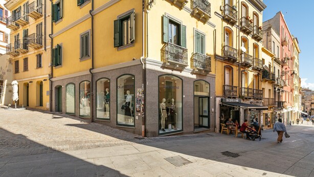 A street with yellow buildings, storefronts, and a pedestrian walkway. - Vico 1° Sulis Apartment 3 with Wi-Fi and Air Conditioning (Cagliari)