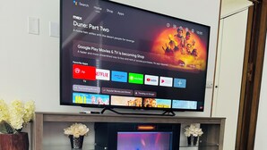 A flat-screen TV mounted on a wooden entertainment center with a fireplace below.