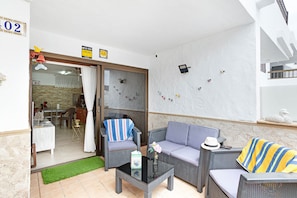 A room with a sofa, armchairs, a coffee table, and a sliding glass door leading to a dining area.