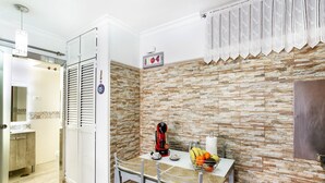 A kitchen with a stone backsplash, a coffee maker, fruit bowl, and a white table. - Vacation Apartment 'Aloe Puerto Rico Beach' with Sea View, Wi-Fi and Air Conditioning (Puertorico -Mogan)