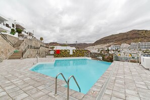 A swimming pool with a stone deck, stairs, and a view of a coastal town. - Vacation Apartment 'Aloe Puerto Rico Beach' with Sea View, Wi-Fi and Air Conditioning (Puertorico -Mogan)