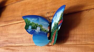 Un papillon aux ailes ornées d’un motif représentant un paysage, posé sur une surface en bois.