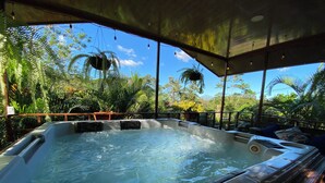 Un bain à remous avec vue sur la végétation luxuriante des tropiques et un ciel dégagé.