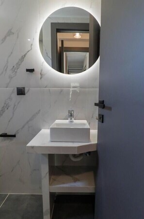A modern bathroom with a white marble wall, a rectangular sink, and a round mirror. - Villa 'Adaman  2' with Private Pool, Wi-Fi and Air Conditioning (Meganisi)