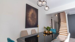 Un comedor moderno con una mesa negra, detalles dorados y un cuadro abstracto de gran tamaño.