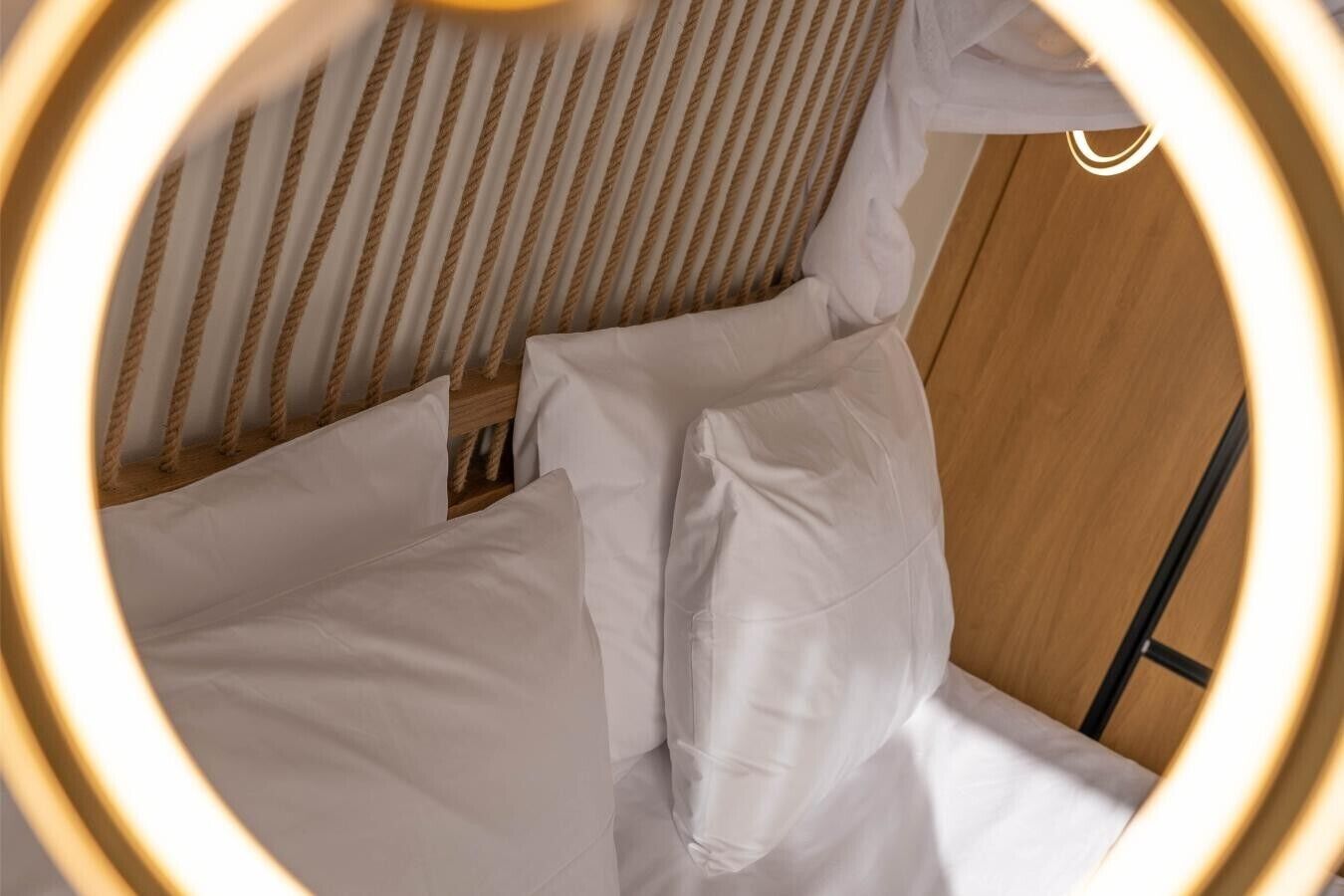 Un letto con biancheria bianca, una testiera in legno e una scala in metallo.