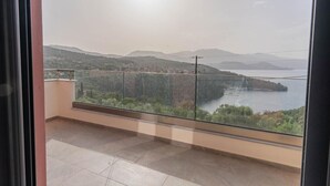 Un balcón con vistas a un paisaje costero, que incluye colinas y una masa de agua.