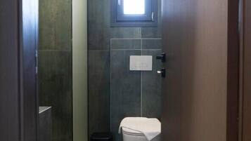 Een badkamer met toilet, prullenbak en douche.