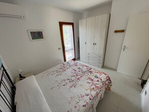 Une chambre à coucher avec un lit, une armoire et une fenêtre ornée de rideaux en dentelle.