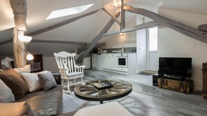 An attic room with a loft bed, a dining table, a TV, and a kitchen area. - Cottage 'Gîte De Pène Blanque' with Mountain View, Private Terrace and Wi-Fi (Arbas)