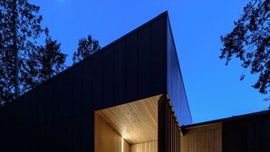 A modern building with a wooden exterior and a glass door entrance. - Tsuga Beach Inn - Waterfront Retreat - NEW - Mahonia Room (Sechelt)