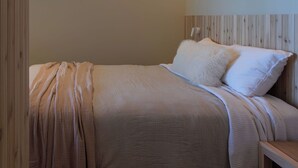 A bedroom with a bed, wooden headboard, and a bedside table. - Tsuga Beach Inn - Waterfront Retreat - NEW - Mahonia Room (Sechelt)