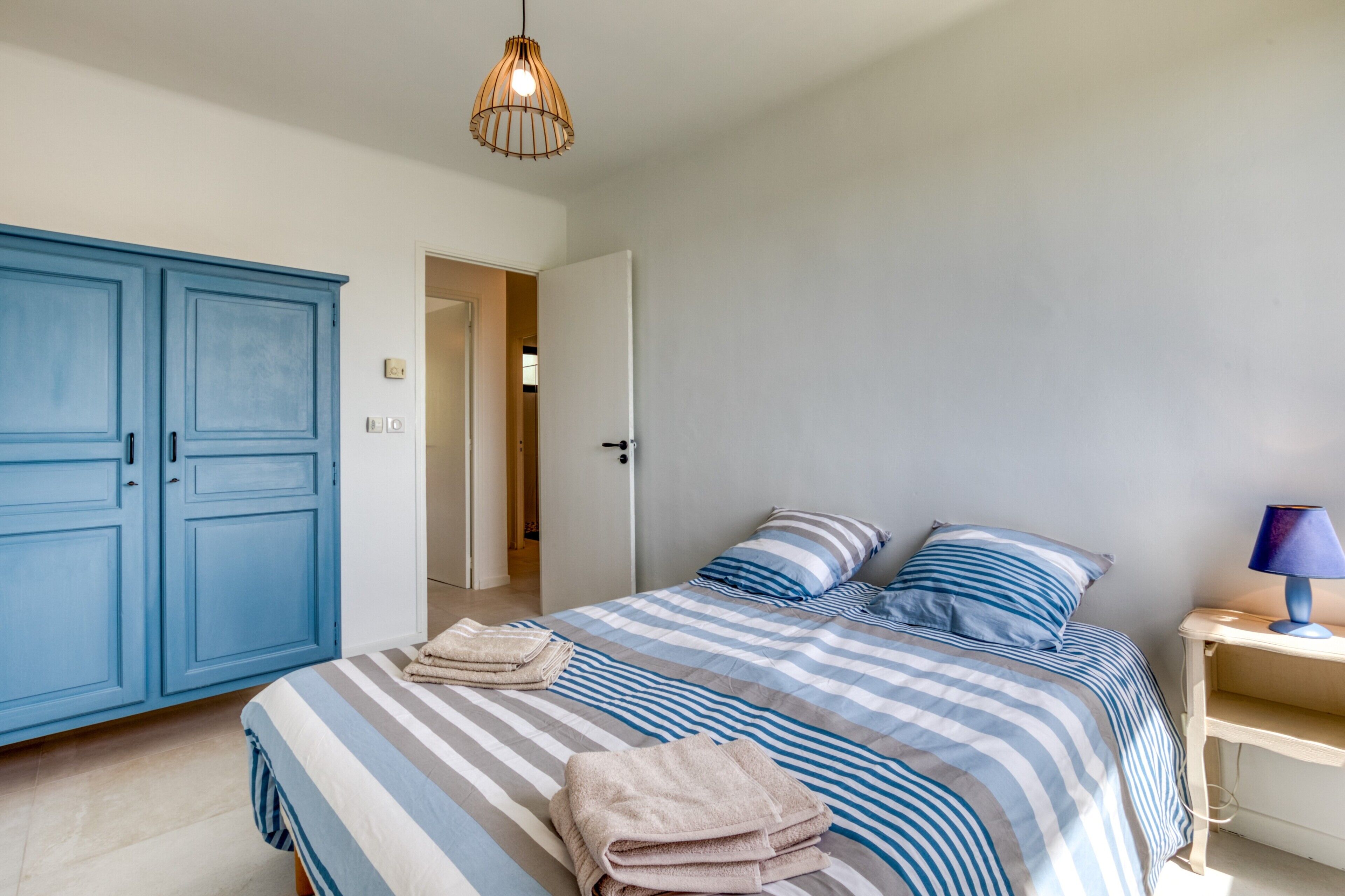 Une chambre à coucher avec un lit, une armoire, une table de chevet et une lampe.
