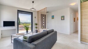 Un saló modern amb un sofà, televisió i plantes en testos.