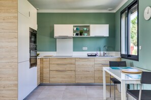 Eine kompakte Küche mit integrierten Geräten, ein Essbereich mit Tisch und Stühlen sowie ein Fenster mit Blick.