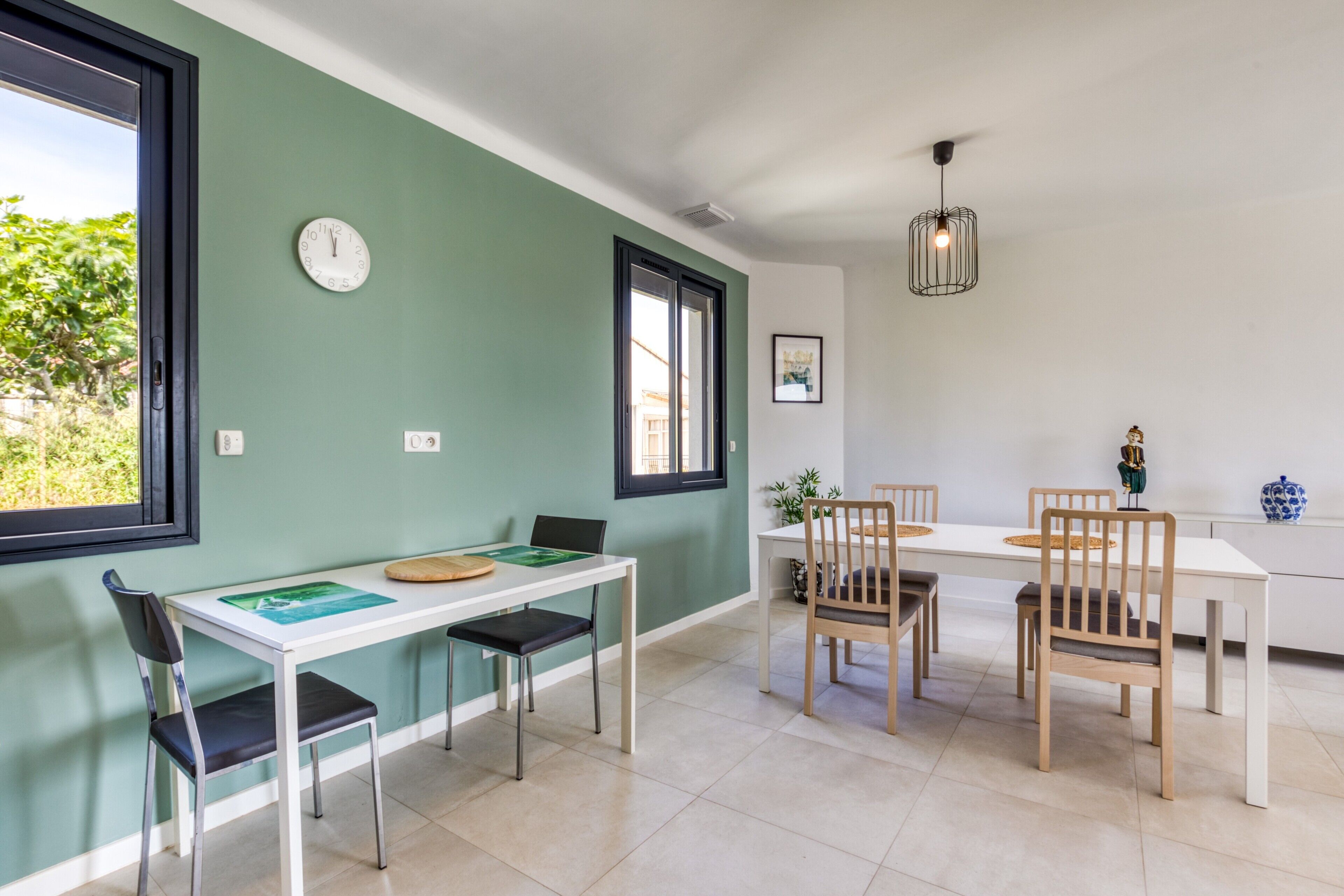 Un comedor con una mesa blanca, sillas y un reloj en la pared.