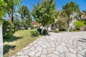 A paved courtyard with stone flooring, surrounded by greenery and trees.