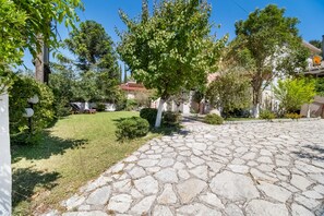 A paved courtyard with stone flooring, surrounded by greenery and trees.