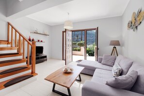 A modern living room with a staircase, a sofa, a coffee table, and a television.