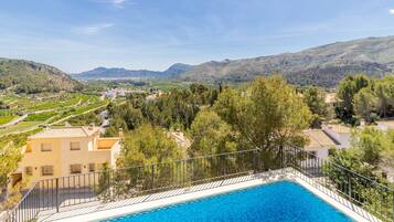 A swimming pool with a view of a mountainous landscape and residential buildings.