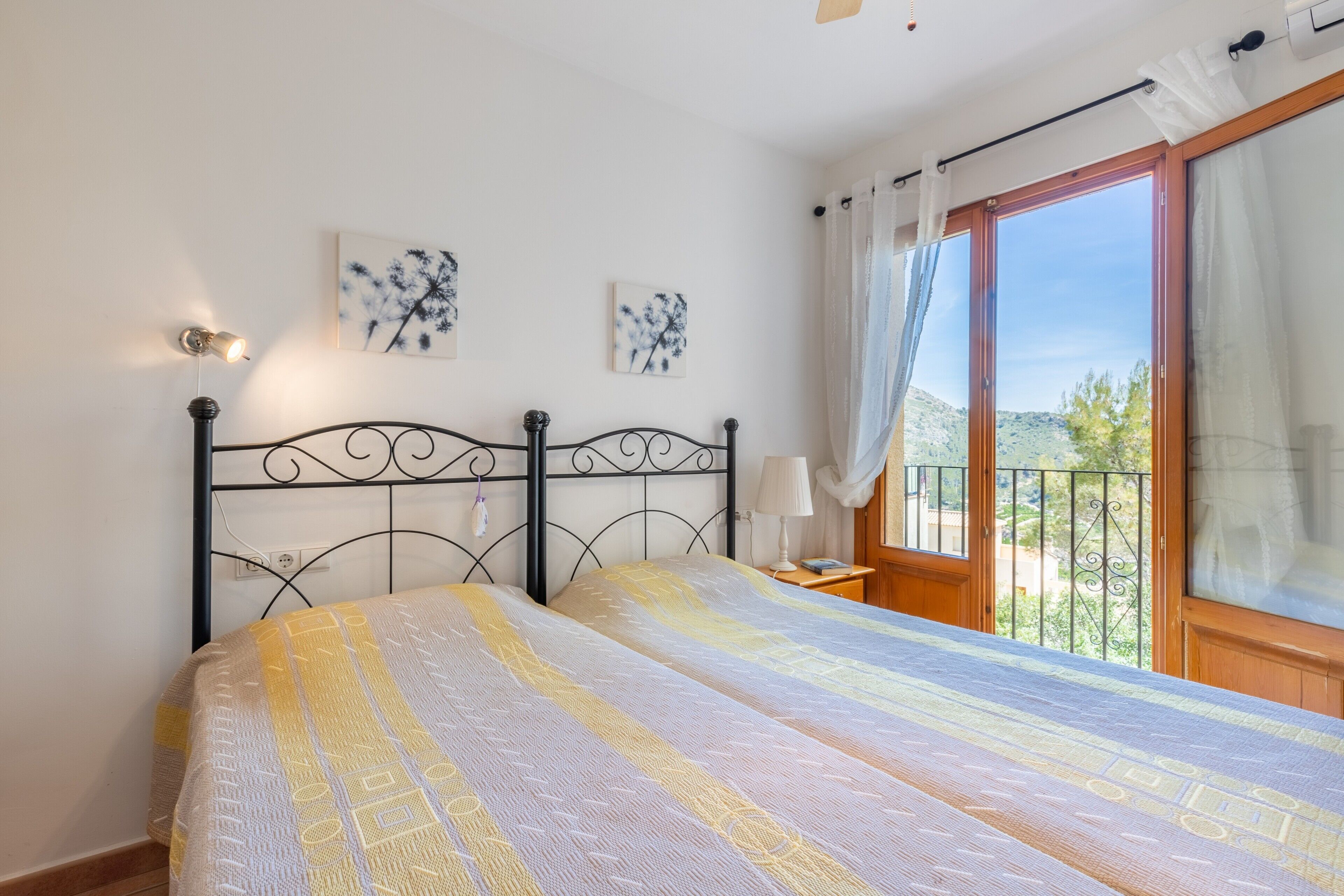 Ein Schlafzimmer mit Bett, Nachttisch, Lampe und einem Fenster mit Vorhängen.