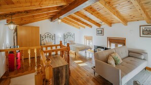 A wooden ceiling, a sofa, a bed, a dining table, and a staircase.