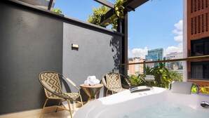 A rooftop terrace with a hot tub, wicker chairs, and a small table with towels. - Golden Valley Hotel (Medellín)