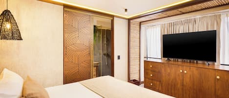 A bedroom with a bed, a TV on a wooden dresser, and a patterned wall.