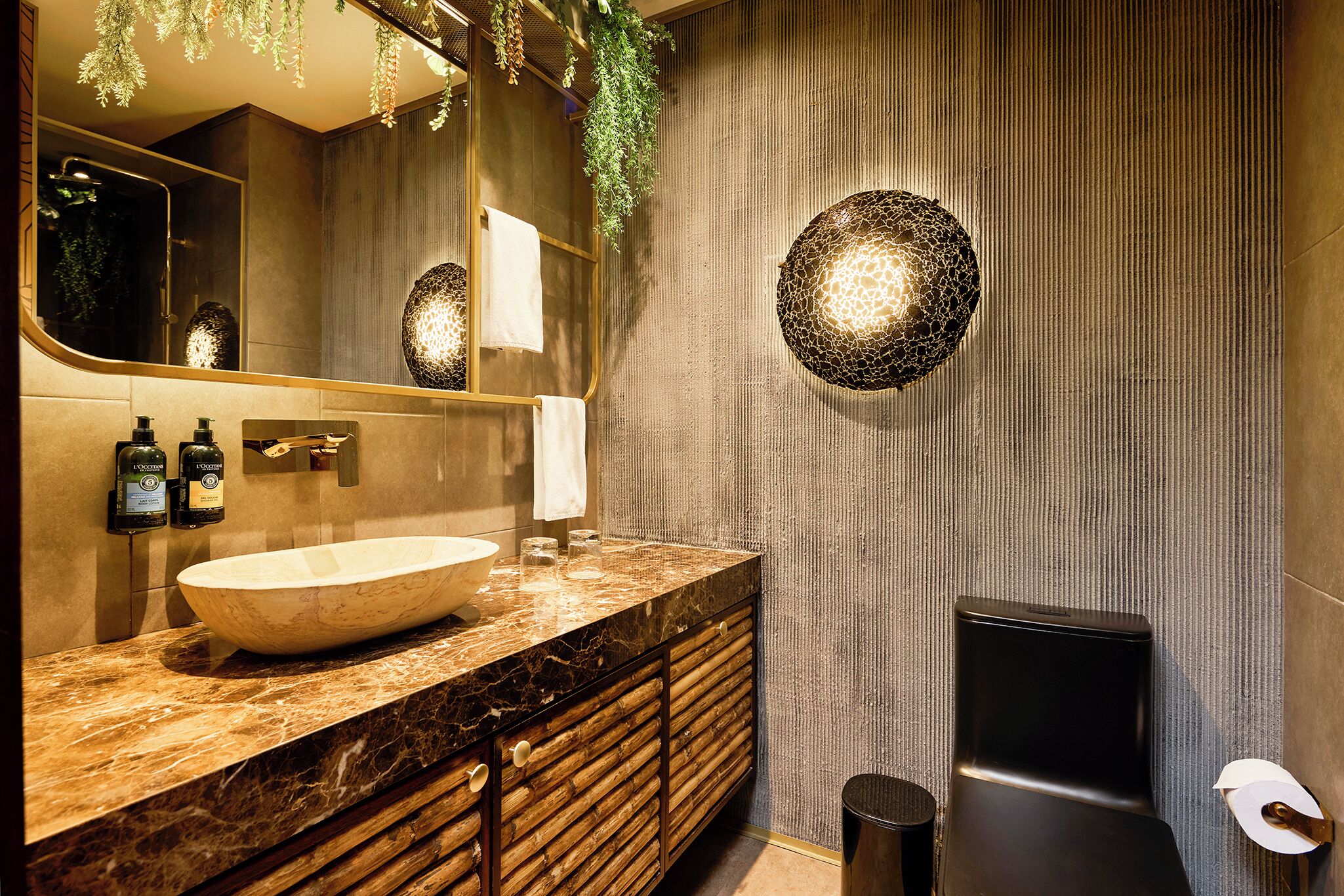 A modern bathroom with a marble sink, wooden vanity, a large mirror, and a textured wall.