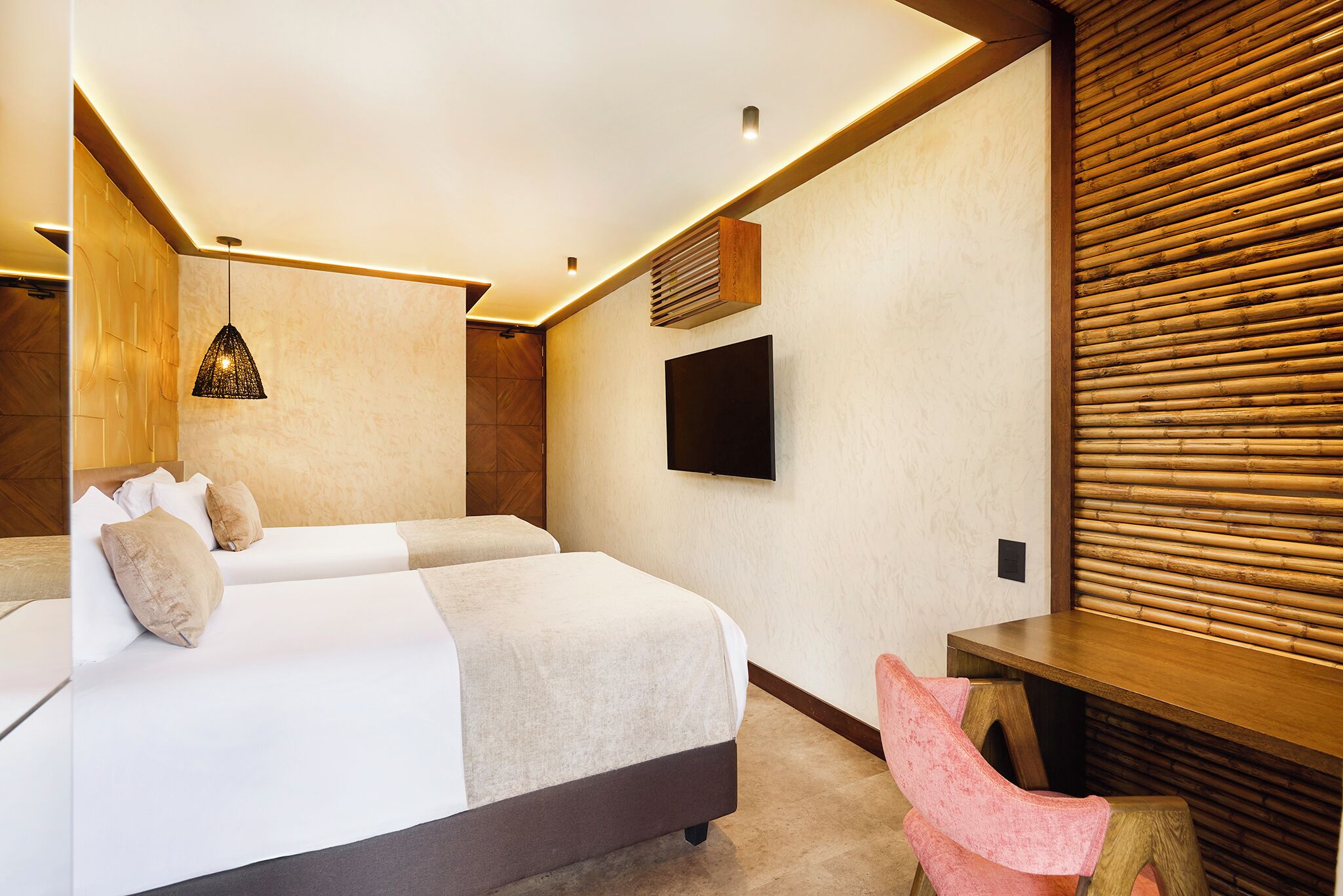 A modern hotel room with a large bed, a desk, a television, and a wooden wall panel.