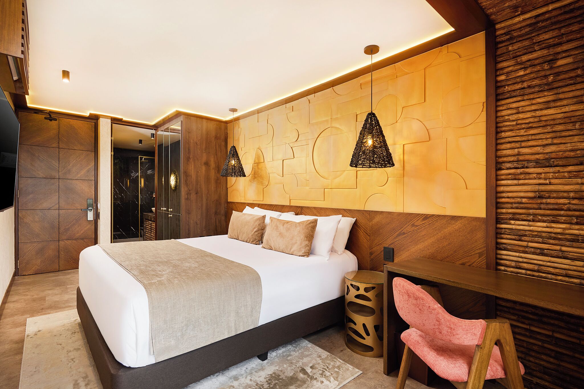 Une chambre moderne avec un grand lit, une tête de lit en bois, deux lampes suspendues, un bureau en bois et une chaise rose.