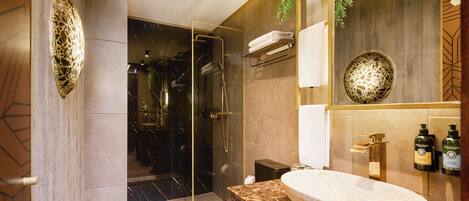 A modern bathroom with a glass-enclosed shower, a marble sink, and a wall-mounted mirror.