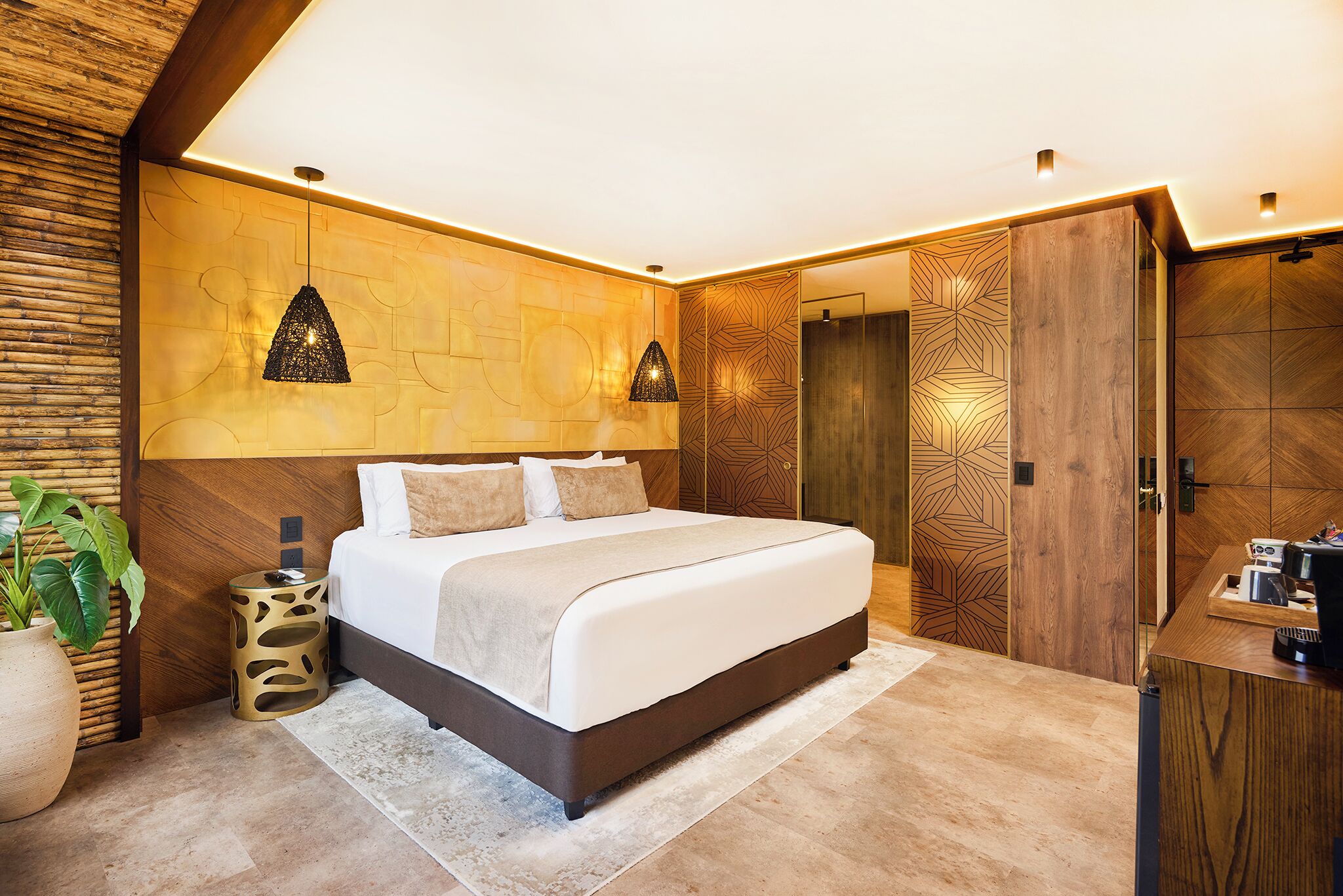 A modern bedroom with a large bed, a bedside table, a wall-mounted lamp, and a wooden door.