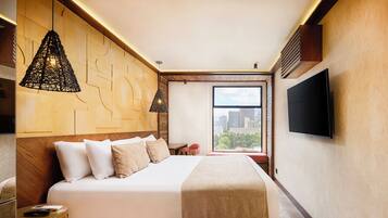 Una habitación de hotel moderna con una cama grande, un televisor, vistas a la ciudad y una pared con una textura original.
