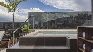 A rooftop pool with a cityscape view, a metal railing, and a wooden shelf with towels. - Golden Valley Hotel (Medellín)