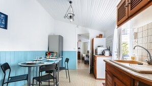 A kitchen with a dining table, chairs, a refrigerator, and a sink.