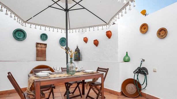 Un espace repas comprenant une table, des chaises et un parasol suspendu.