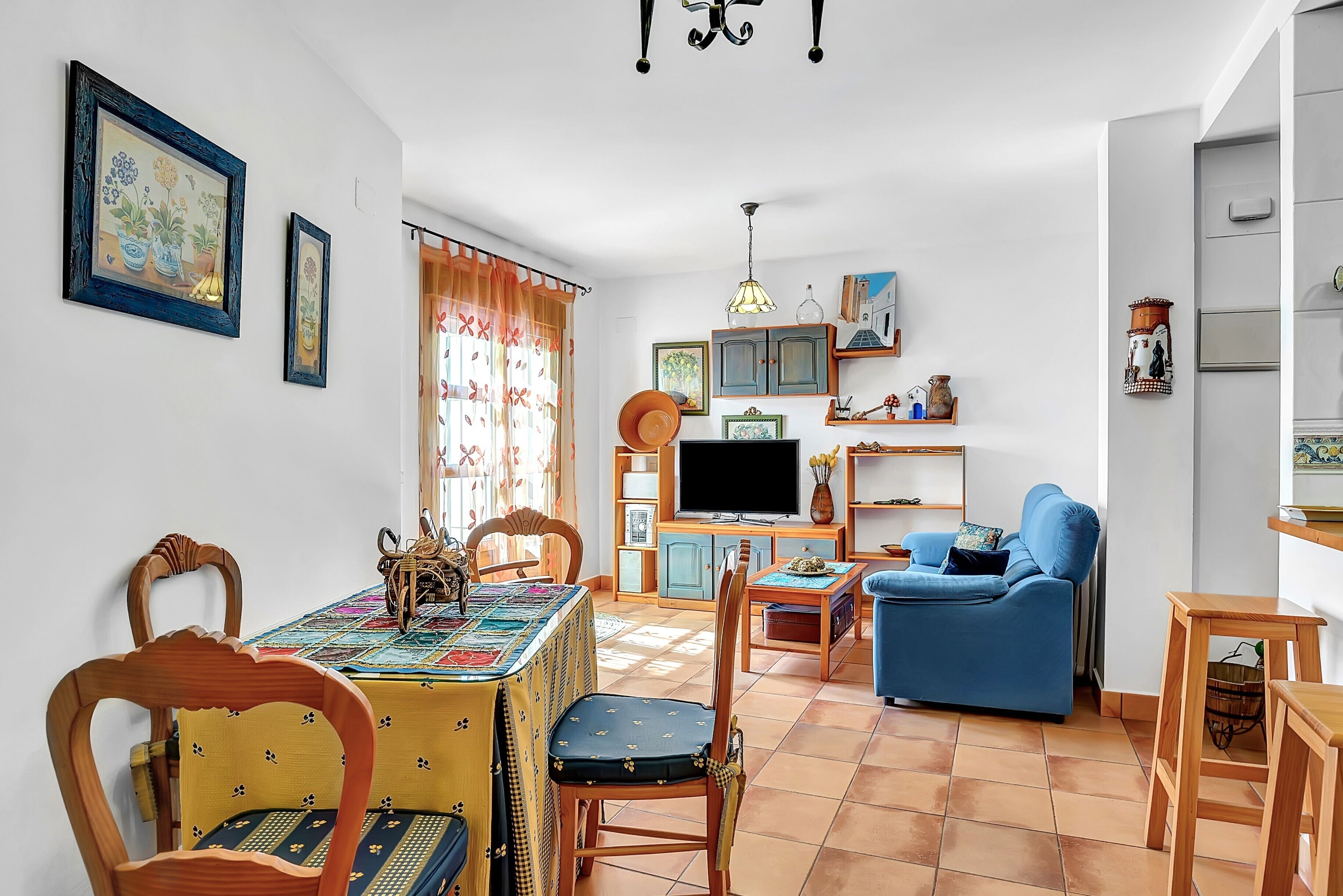 Un comedor con una mesa, sillas, un televisor, un sofá y un sillón azul.