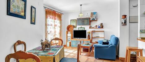 Un comedor con una mesa, sillas, un televisor, un sofá y un sillón azul.