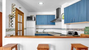 Une cuisine avec des armoires bleues, un plan de travail en bois, un four à micro-ondes et un grille-pain.