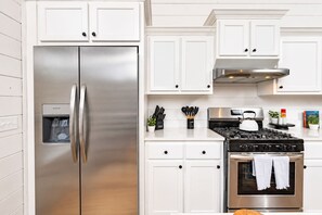 A modern kitchen with white cabinetry, stainless steel appliances, and a gas stove.