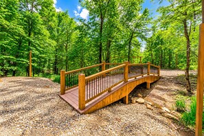 A wooden bridge in a forested area with gravel ground.