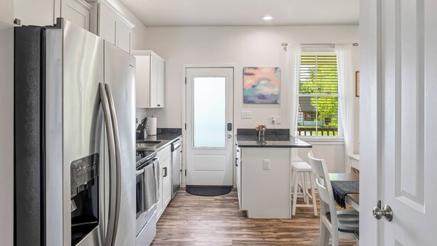 Una cucina moderna con mobili bianchi, elettrodomestici in acciaio inossidabile e pavimento in legno.