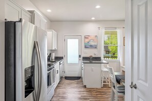 A modern kitchen with white cabinetry, stainless steel appliances, and a wooden floor. - Powell House! 3 mi from Purina (Labadie)