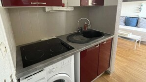 A compact kitchen with a washing machine, a sink, and a stove.