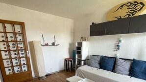 A modern living room with a wooden floor, a white sofa with blue cushions, a white coffee table, and a wooden cabinet with decorative items.