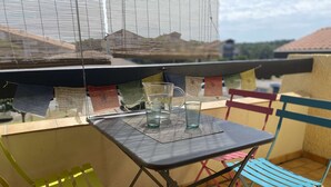 A small outdoor table with two glasses and a pitcher, surrounded by colorful chairs.