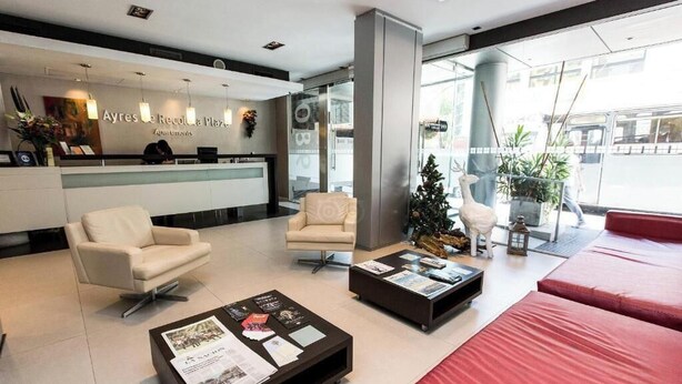 Ein moderner Empfangsbereich mit einer Rezeption, zwei Sofas, einem Couchtisch und einer roten Lounge-Ecke.