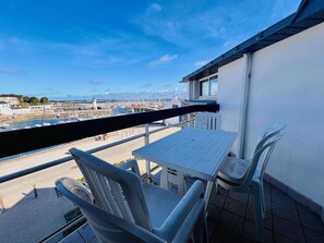Enjoy the serene marina views from this balcony, featuring a table and two chairs.