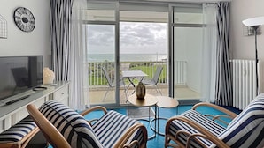 A balcony with a view of the sea, a TV, and striped furniture. - QUIBERON - Studio - 38m² - Sea view (QUIBERON)